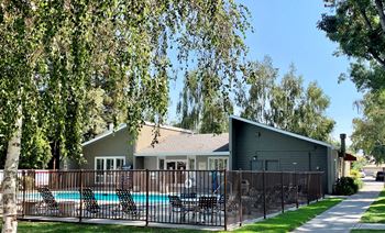 A house with a pool surrounded by a fence and trees.
